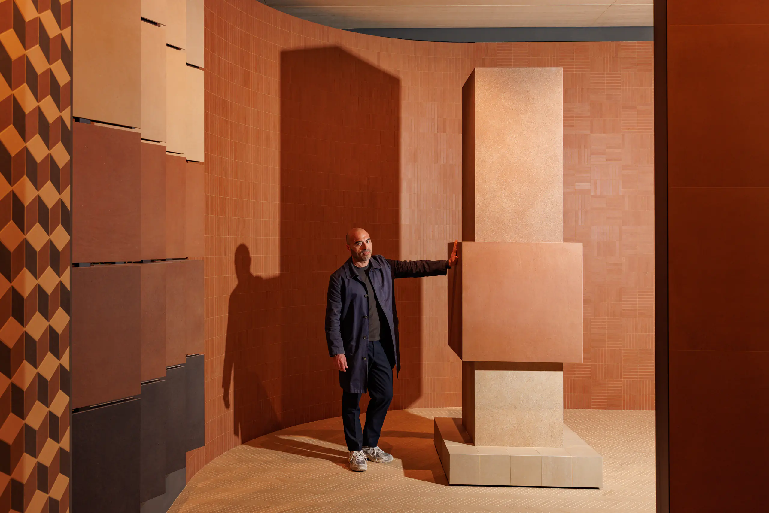 Man in an earth-toned architectural installation with terracotta walls
