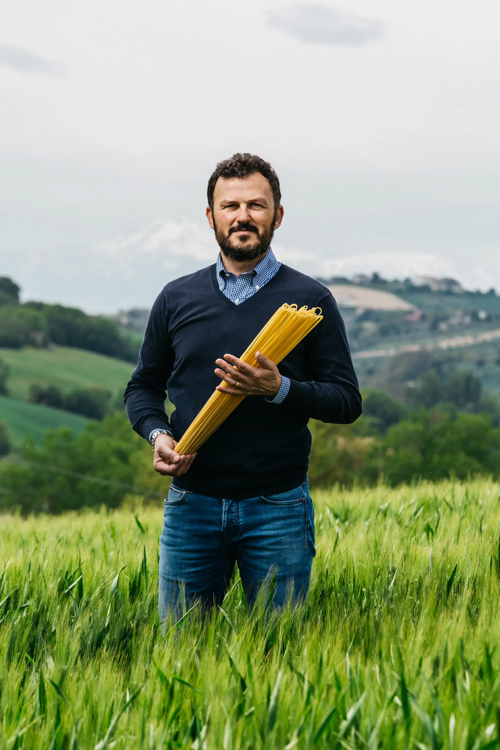 Man holding a bundle of pasta standing in a wheat field