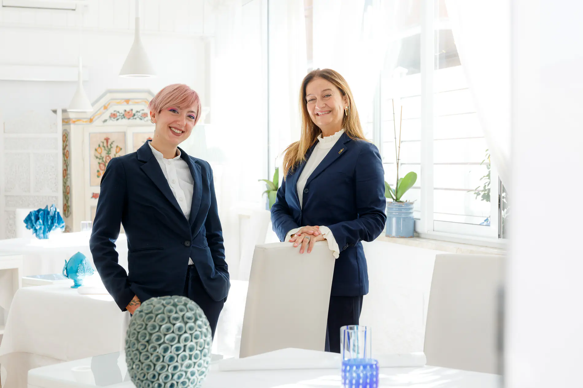 Two women in blazers in a bright elegant dining room