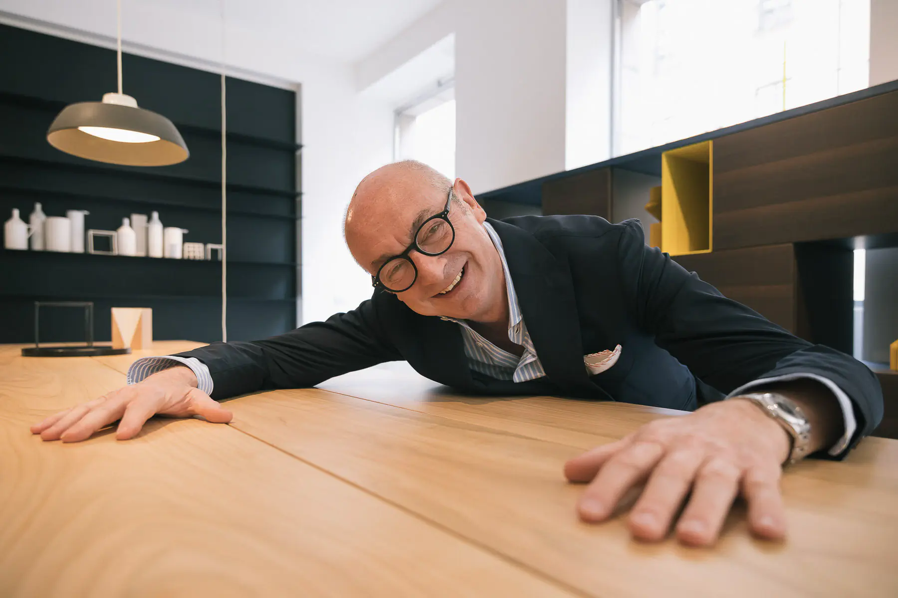 Smiling man in a suit leaning on a wooden table