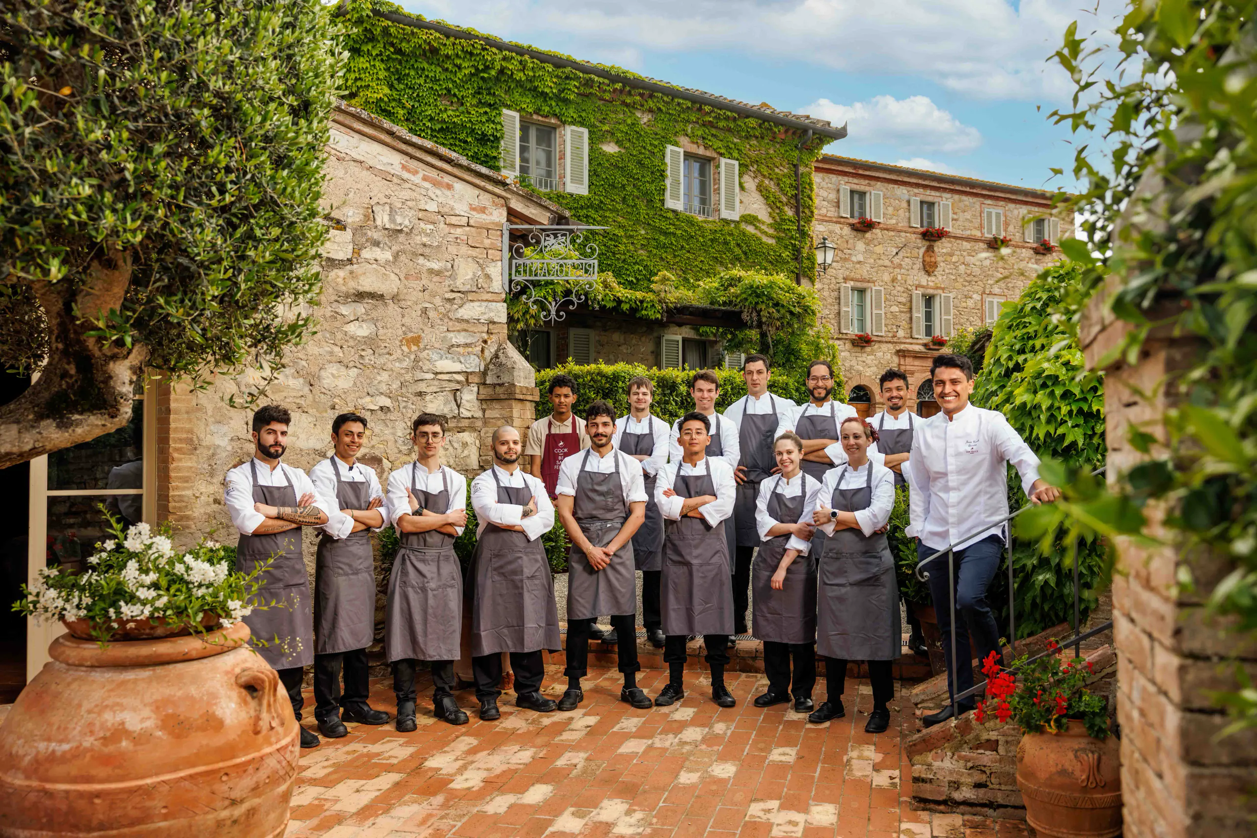Line of staff in aprons in a rustic Tuscan courtyard — Borgo San Felice