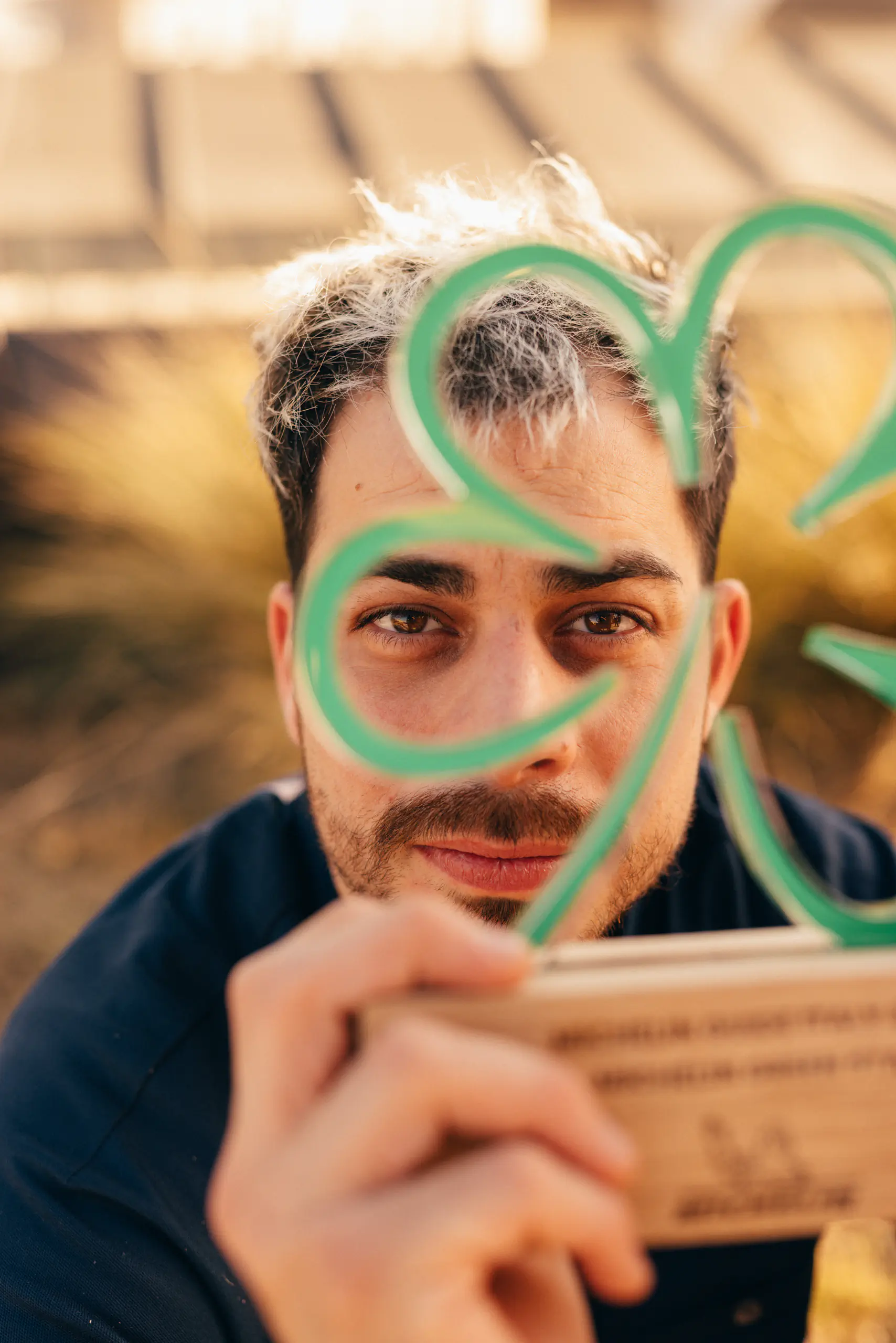 Man holding a coiled green garnish near his face — Horto, Milan