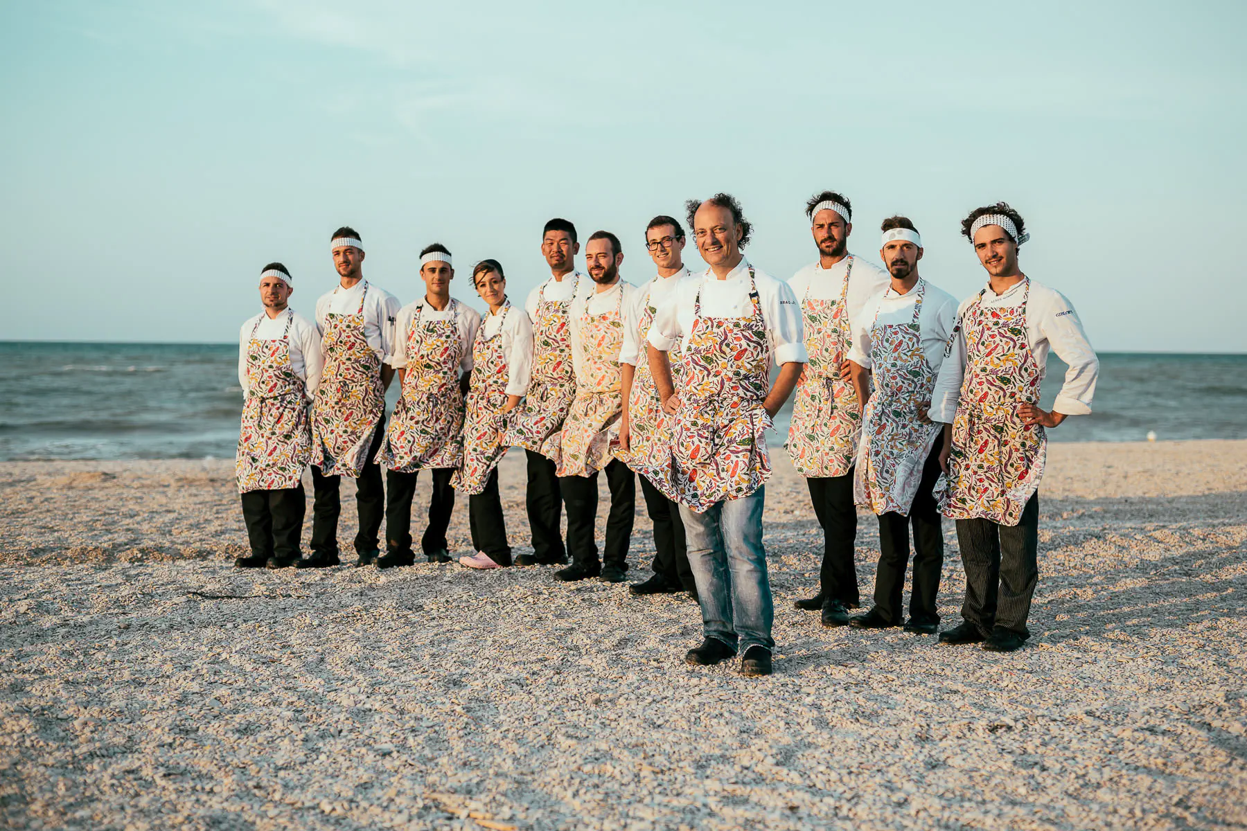 Group of chefs in aprons lined up on a beach