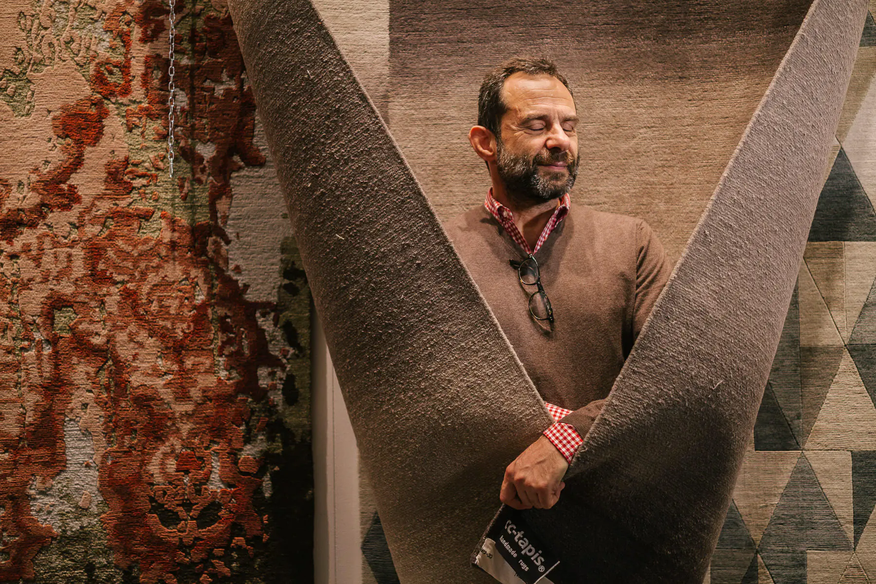 Man in a knit sweater posing against a large rusted metal structure
