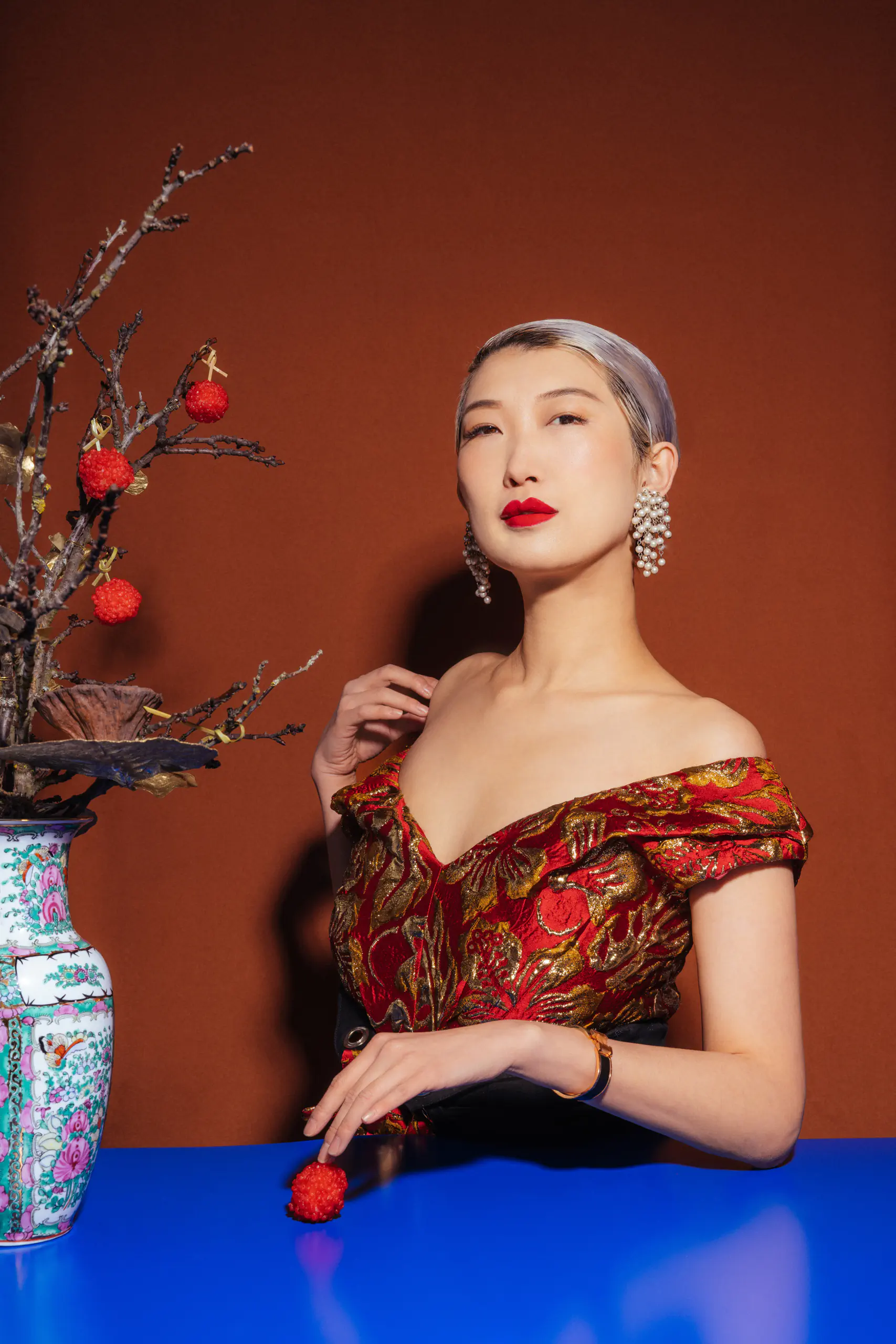 Portrait of Xinge Liu in a patterned dress against a red backdrop